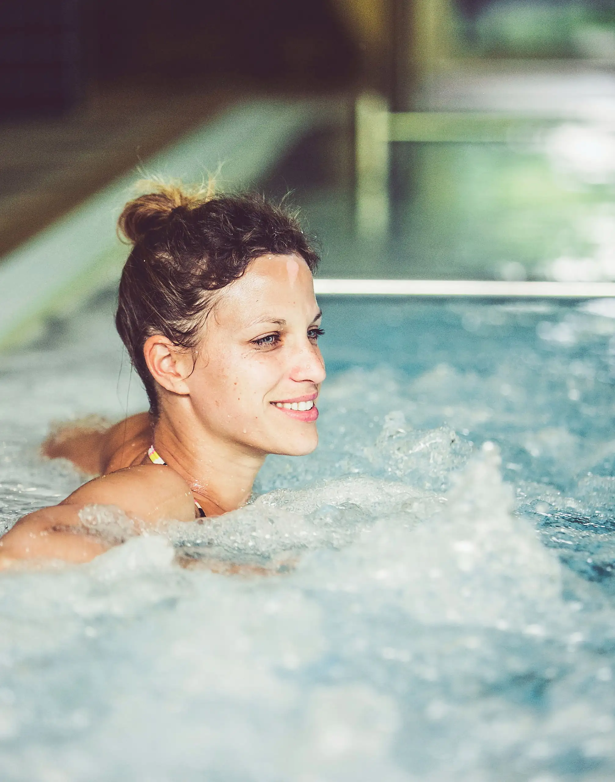 Gast in der sprudelnden Whirlbank des Hallenbads im Schlosshotel Seewirt