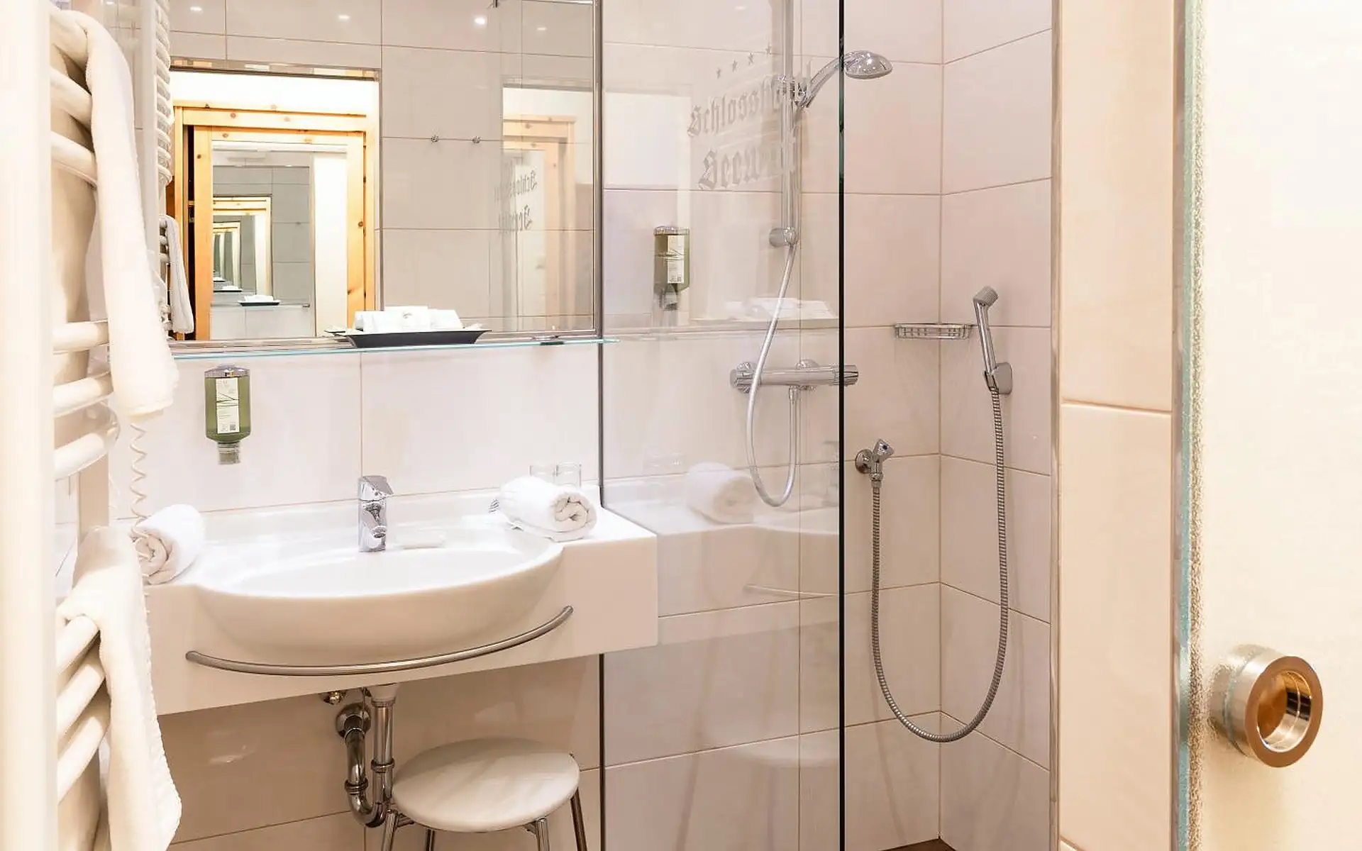 Badezimmer im Schlosshotel Seewirt mit Waschtisch, Spiegel und verglaster Dusche